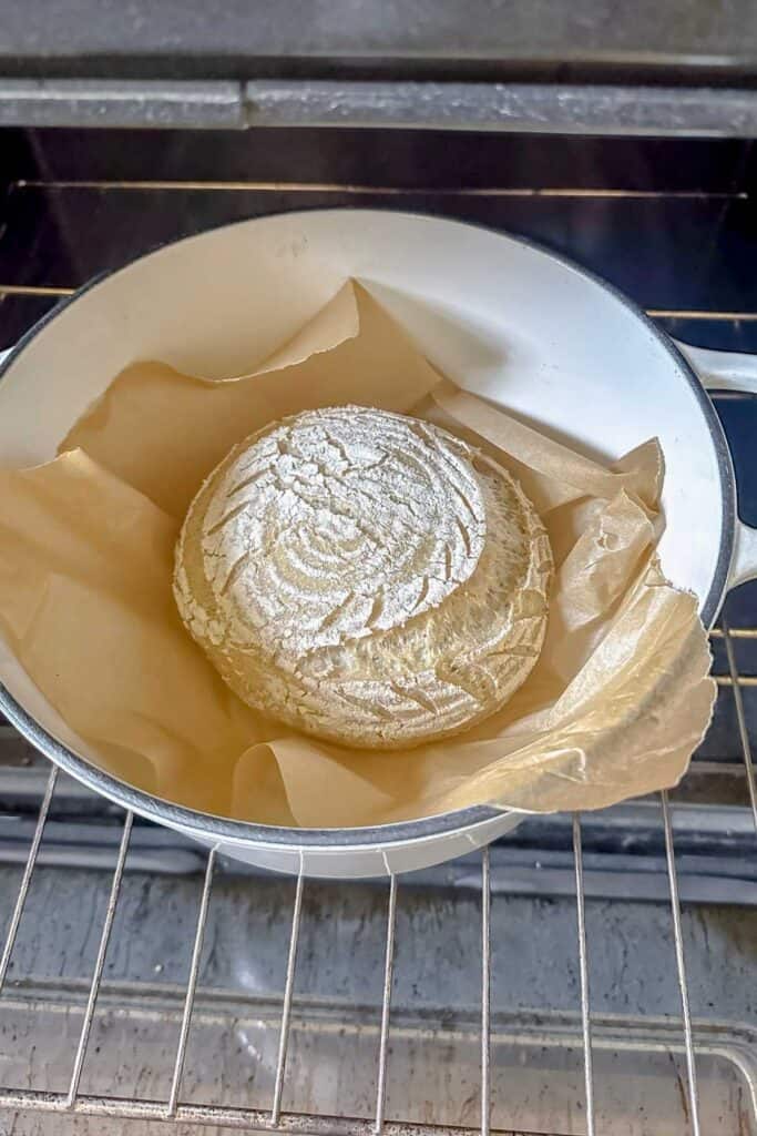 loaf of gluten free sourdough bread in dutch oven with lid off