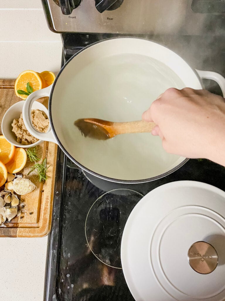 adding salt to boiling water and a hand stirring a wooden spoon