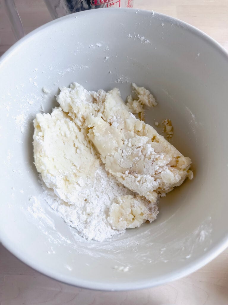mixing melted butter with powdered sugar in ceramic bowl