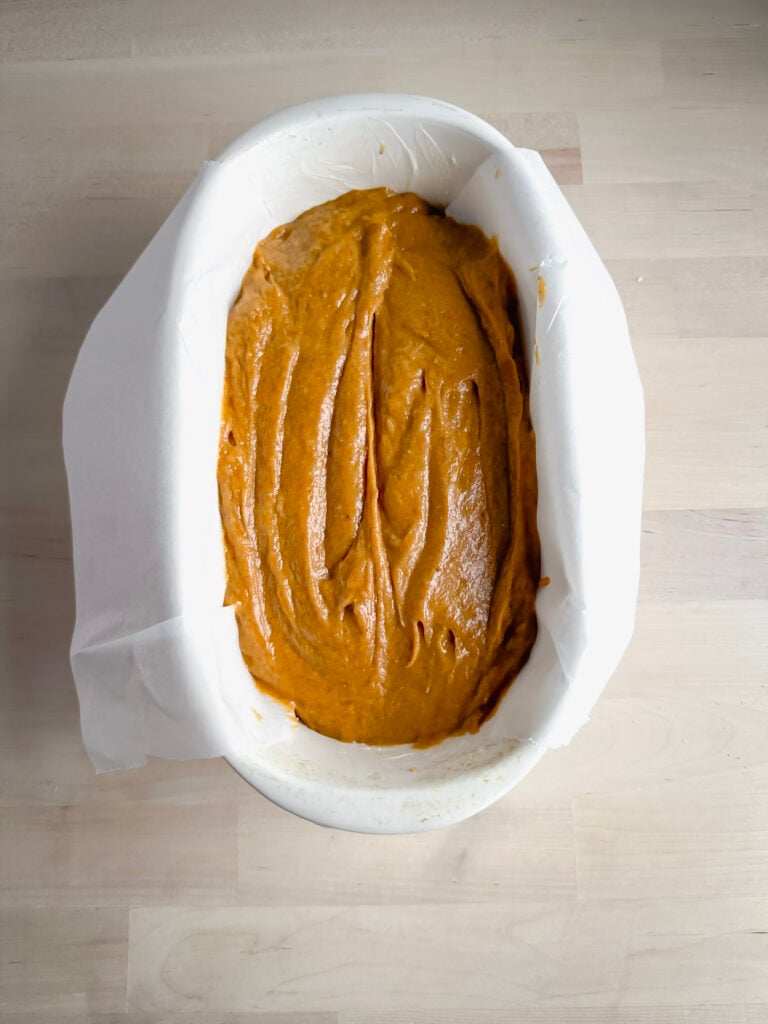white ceramic bread loaf pan with gf pumpkin bread batter in it