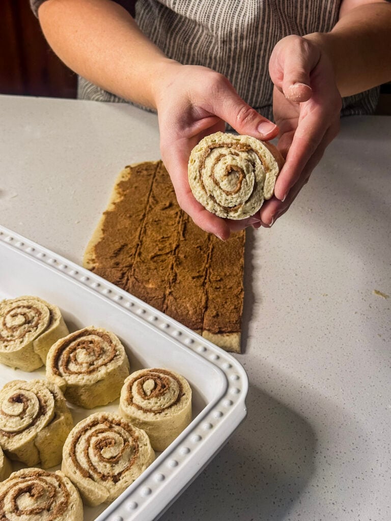 a rolled up cinnamon dough being held in hands
