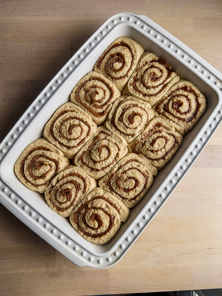 proofed gluten free cinnamon rolls ready to bake in white baking dish