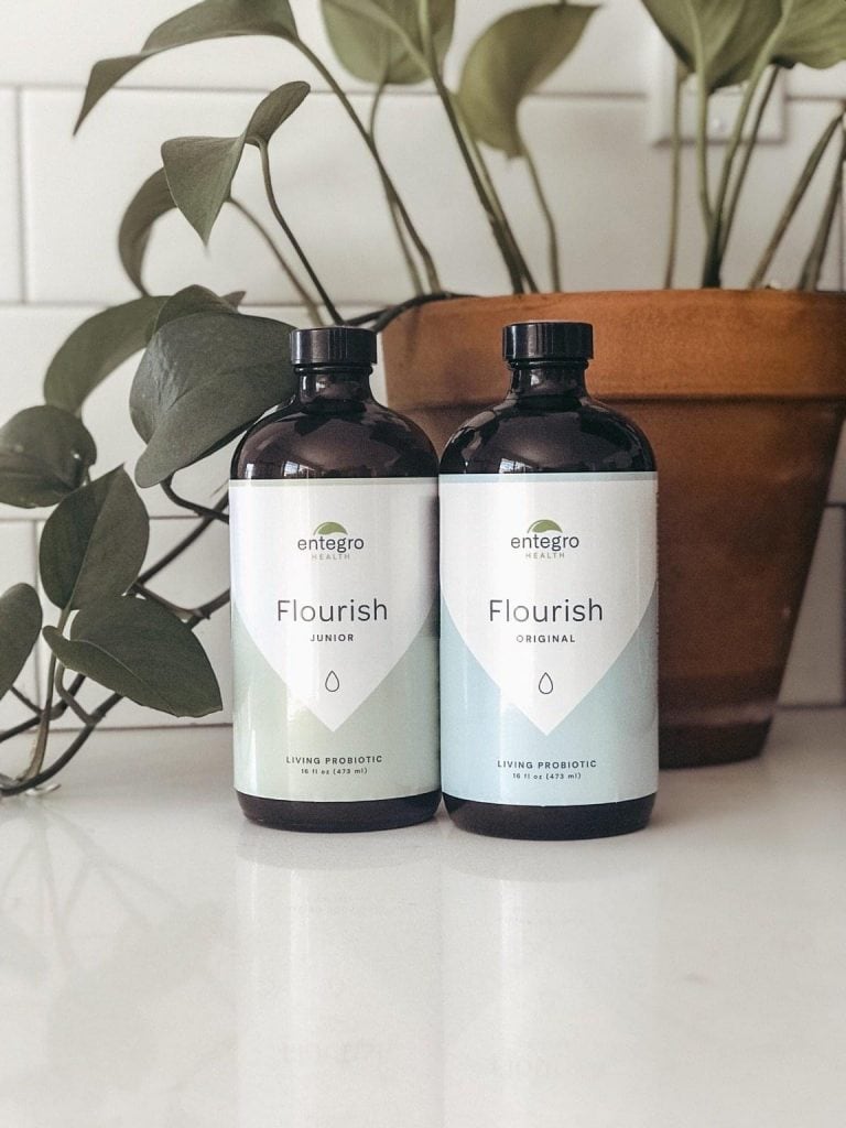 two bottles of Flourish probiotics in front of plant