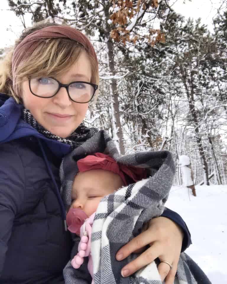 mother holding sleeping baby in snow