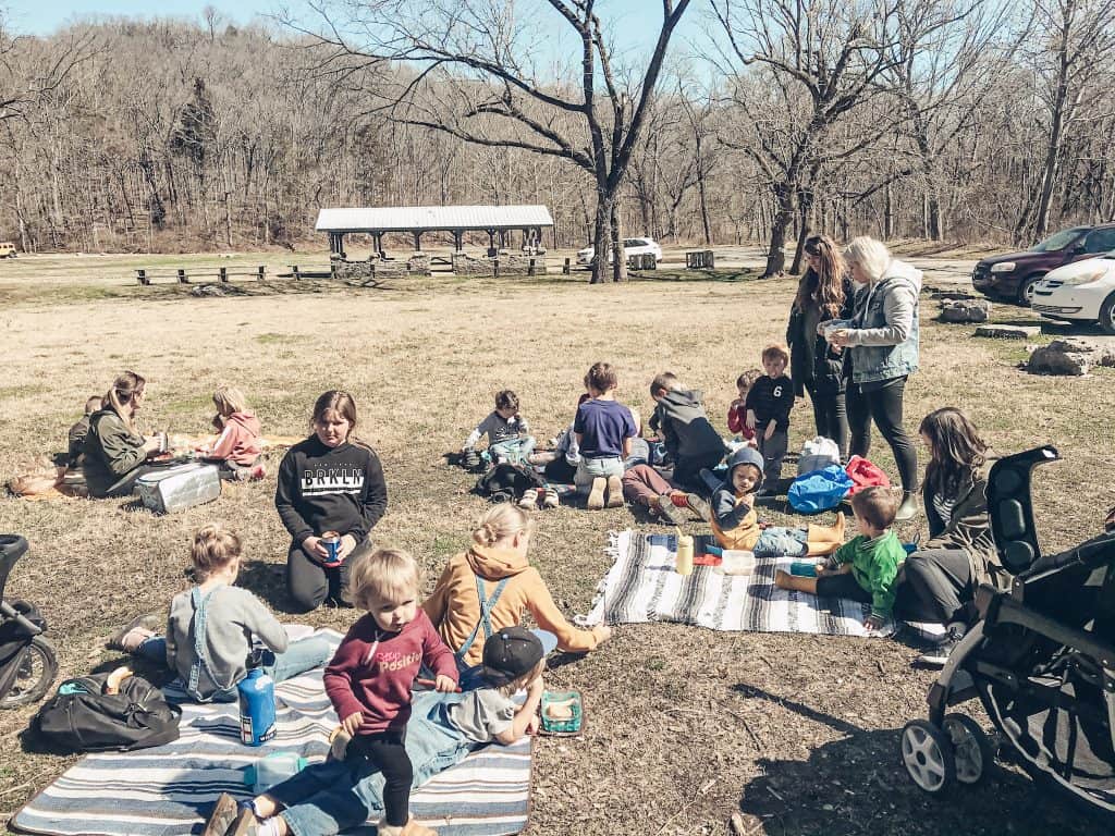 homeschooling families gathered for nature co op sitting on blankets in the grass 