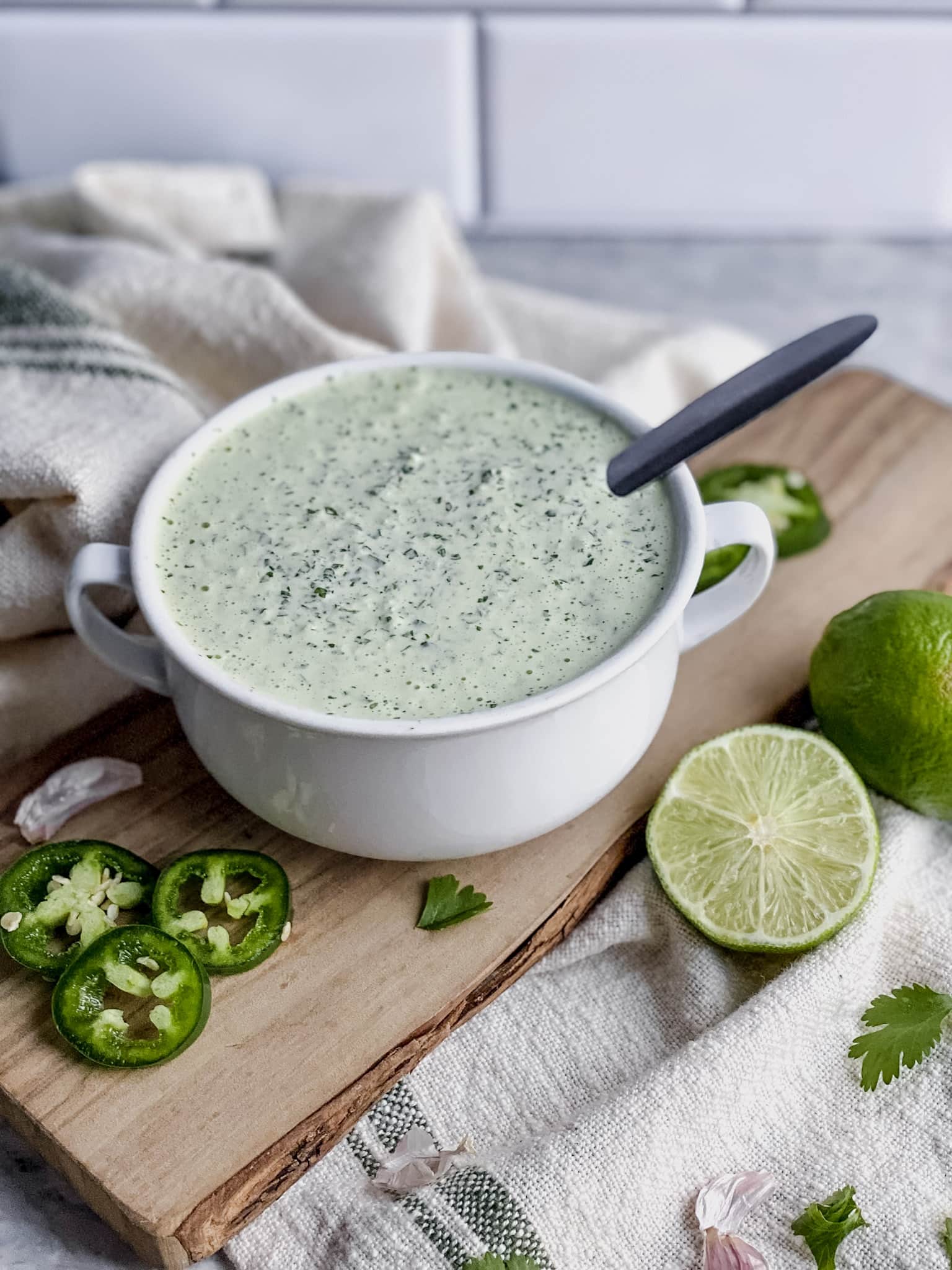 a bowl of cilantro lime crema sauce sits on a cutting board