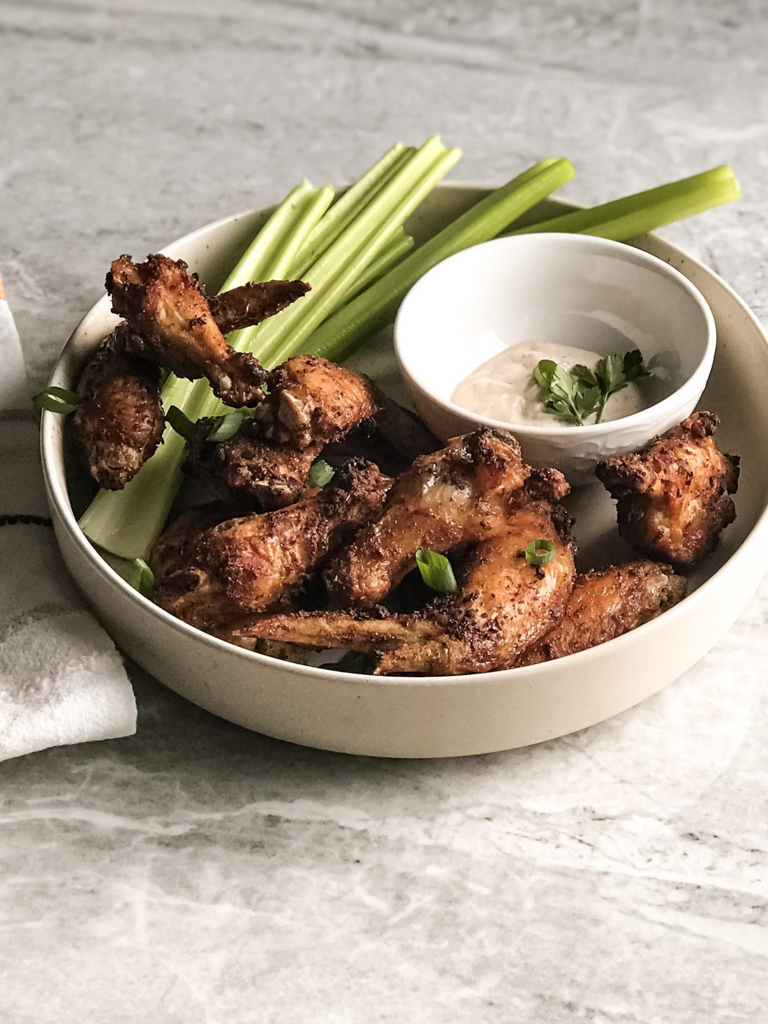 air fried chicken wings in stone bowl with celery and dip on table