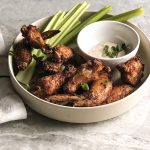 air fried chicken wings in stone bowl with celery and dip on table