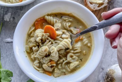 two bowls of creamy gluten free chicken noodle soup with gf bread nearby