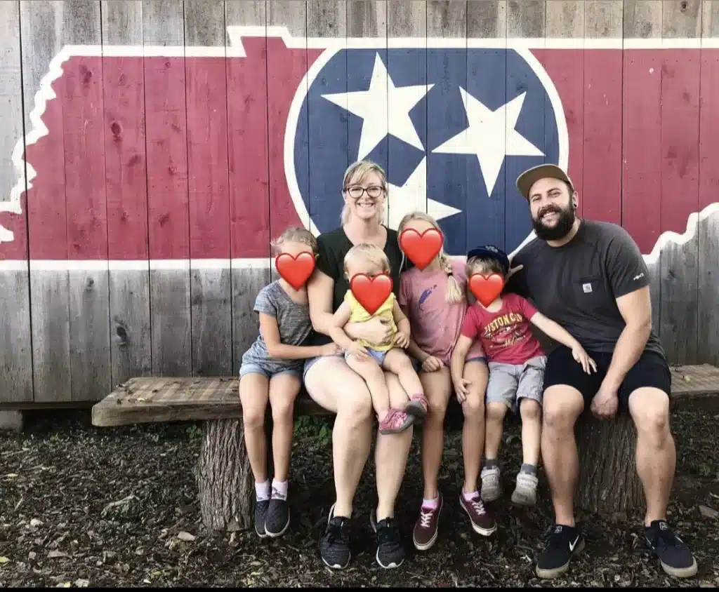 family of 6 sitting on a bench in front of a Tn state mural