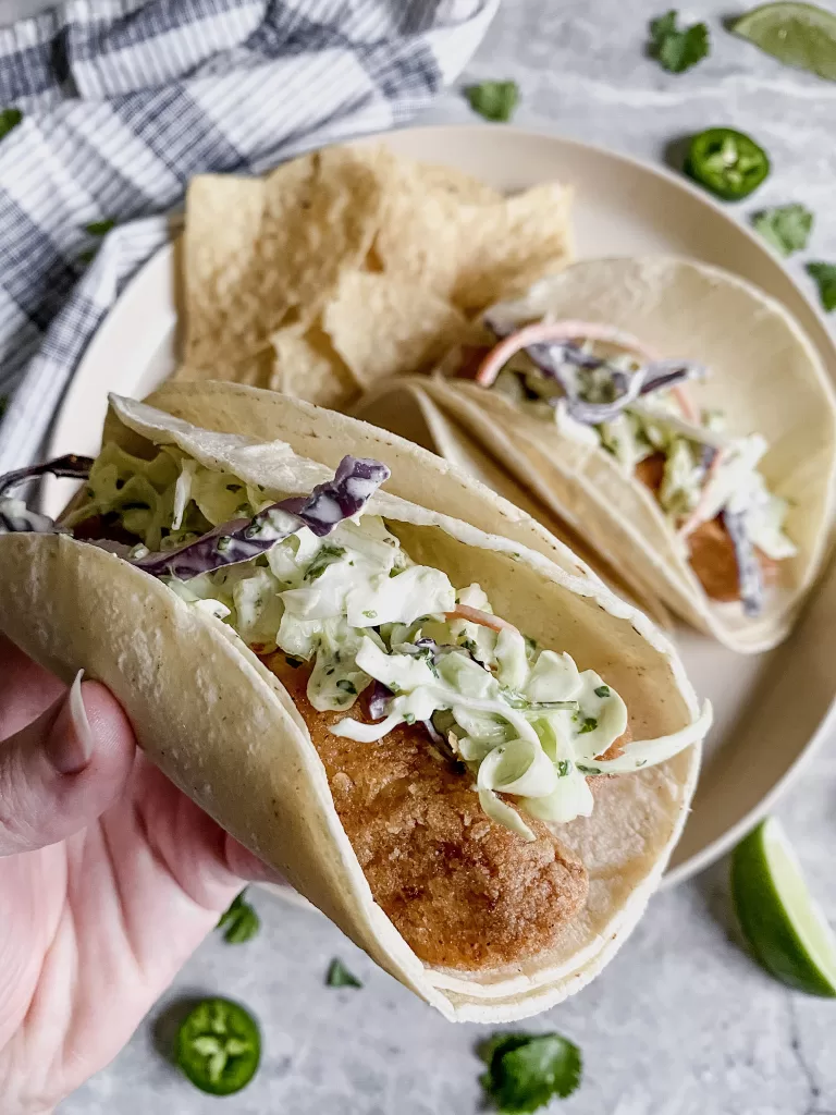 fried fish tacos being held by a hand