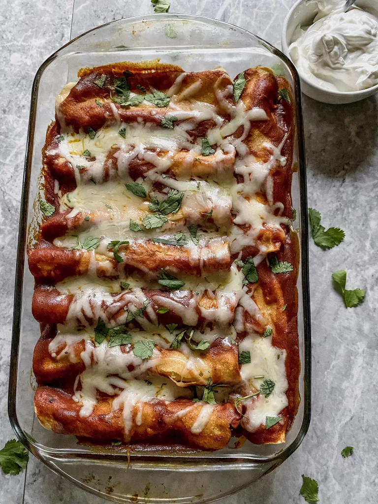 a pan stuffed with gluten free enchiladas with cheese and cilantro on top
