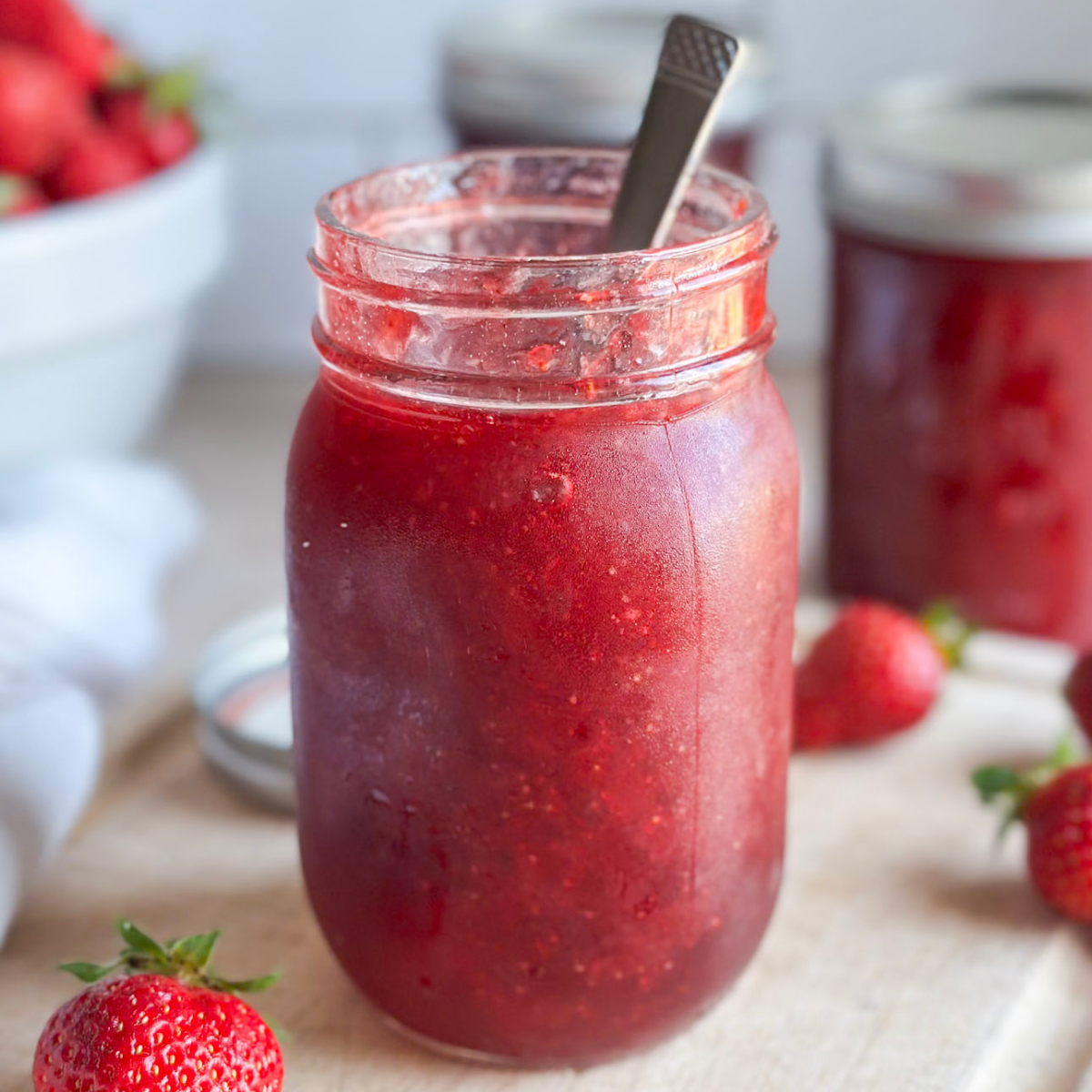 jar of homemade strawberry jam on cutting board