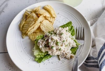 a scoop of gluten free chicken salad on leaves of romaine lettuce with chips on the plate also