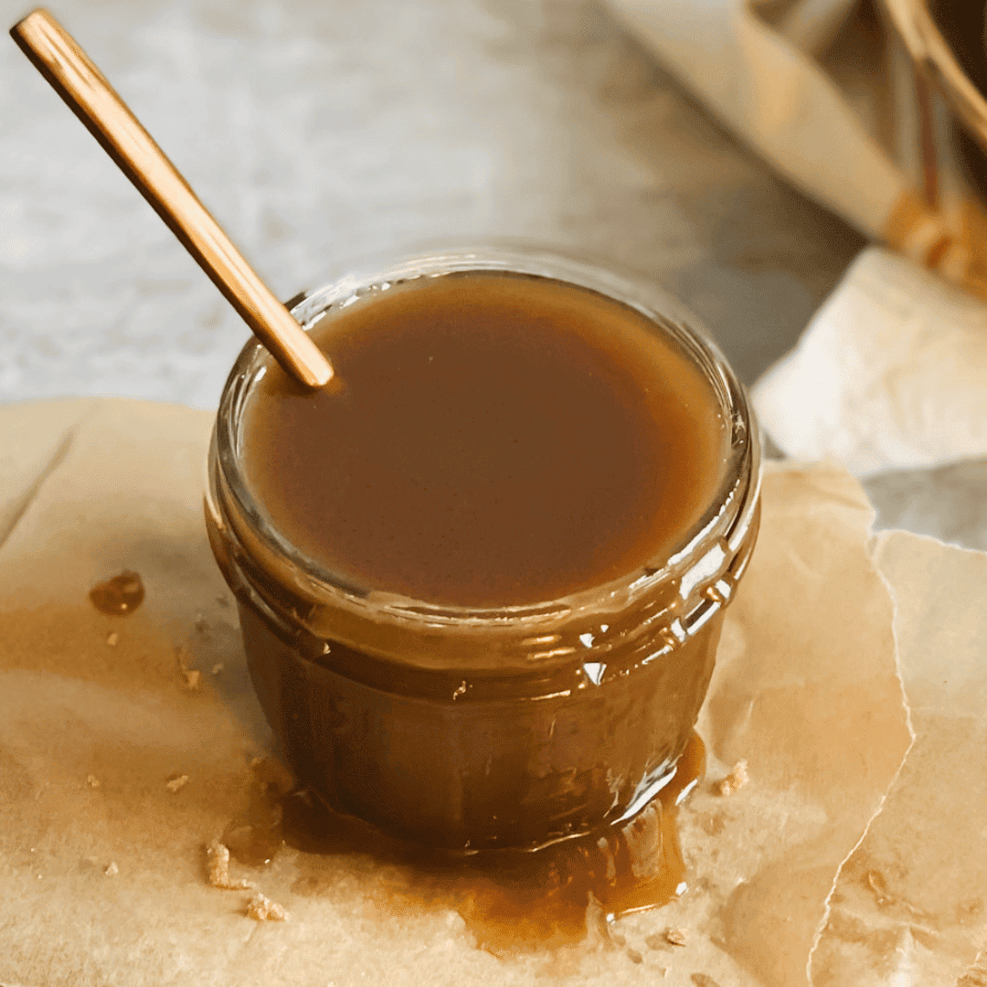 jar of golden vegan caramel sauce sits on cutting board