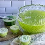 Bowl of green holiday punch with cups filled with sherbet