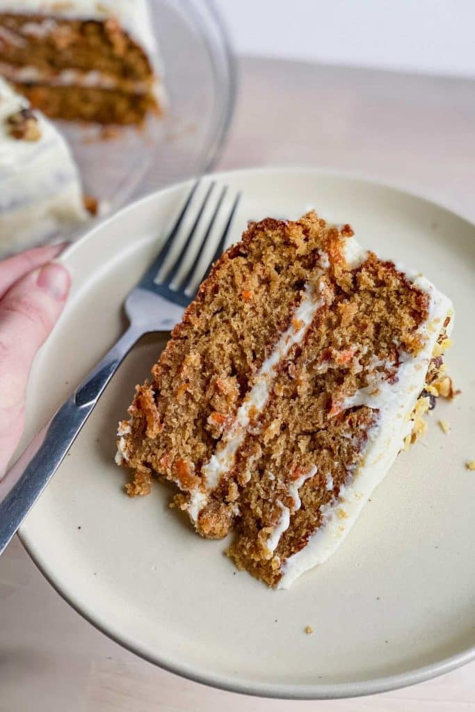 slice of gluten free carrot cake on a white plate with a fork