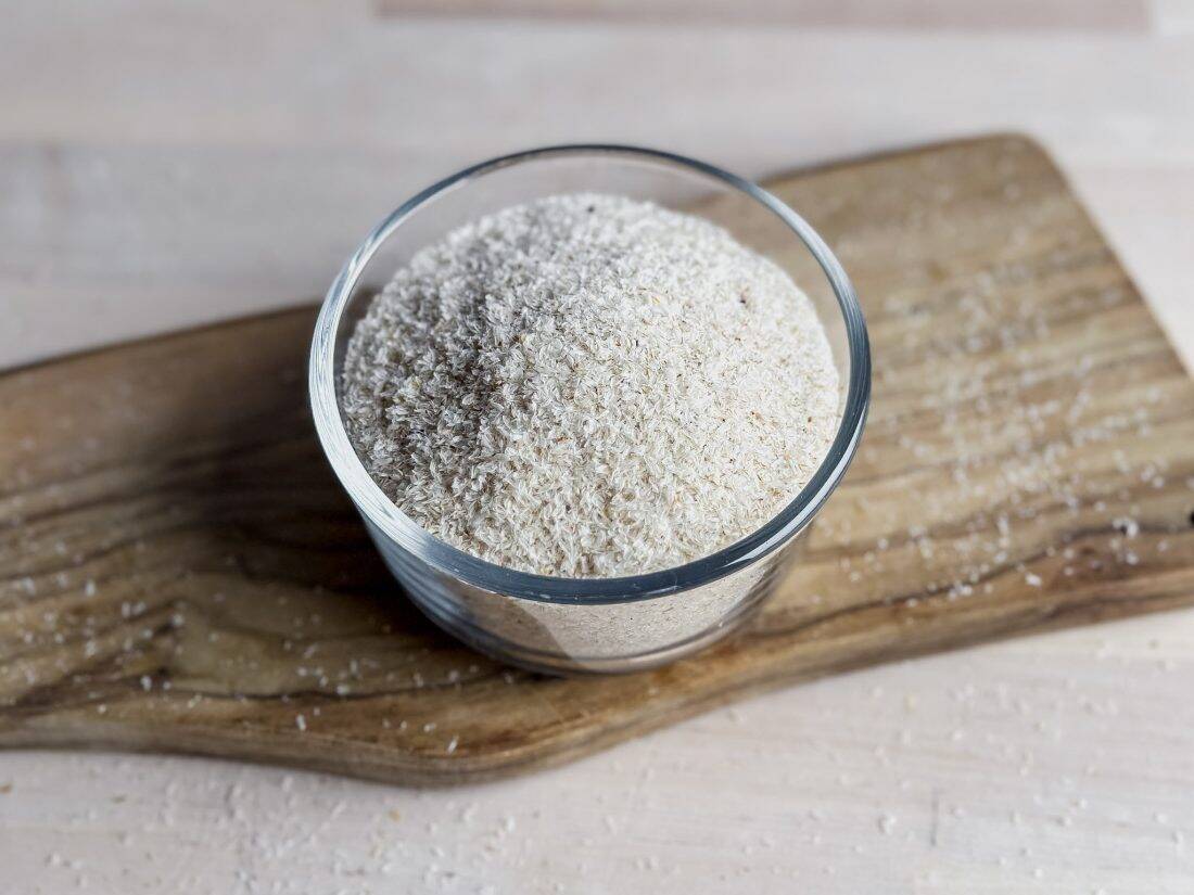 glass bowl of whole psyllium husk on wooden board
