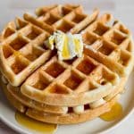 stack of three gluten free sourdough waffles with a pat of butter and maple syrup running down the sides