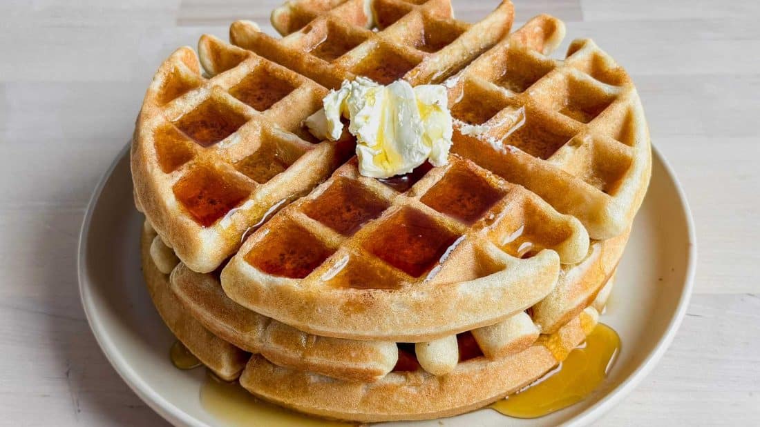 stack of sourdough waffles with butter and maple syrup