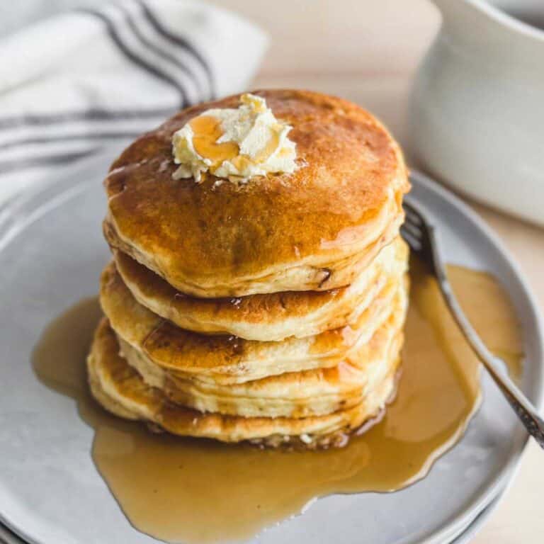 stack of gluten free pancakes on a gray plate with maple syrup