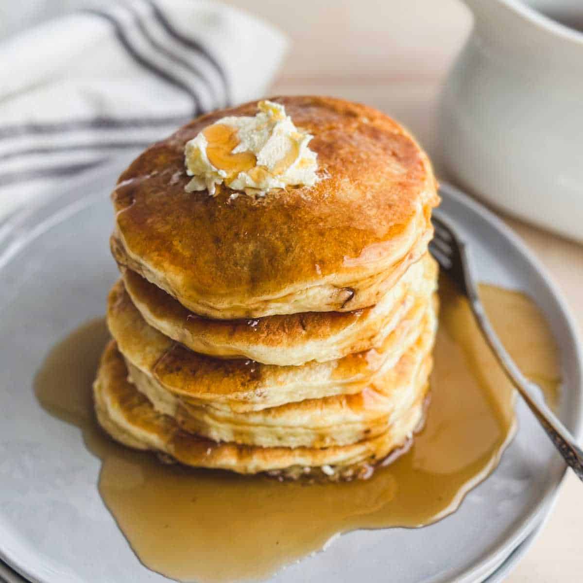 stack of gluten free pancakes on a gray plate with maple syrup