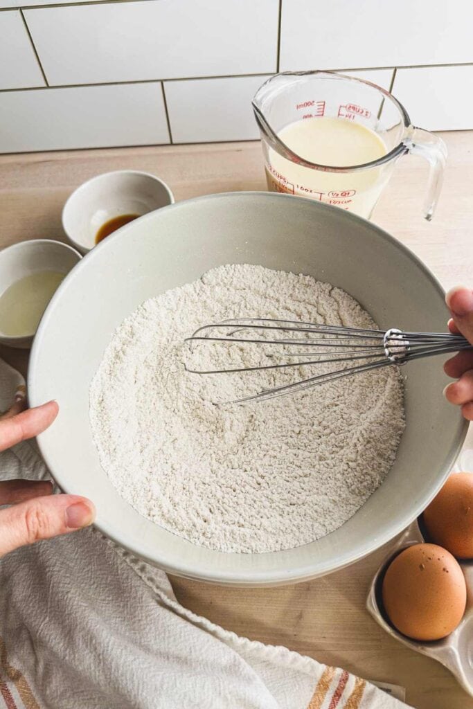 white ceramic bowl with dry ingredients and a whisk