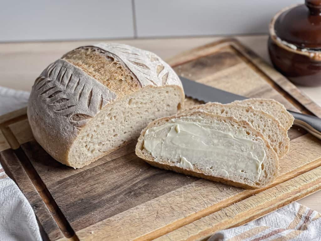 loaf of gluten free artisan bread round loaf on a cutting board with slices next to it