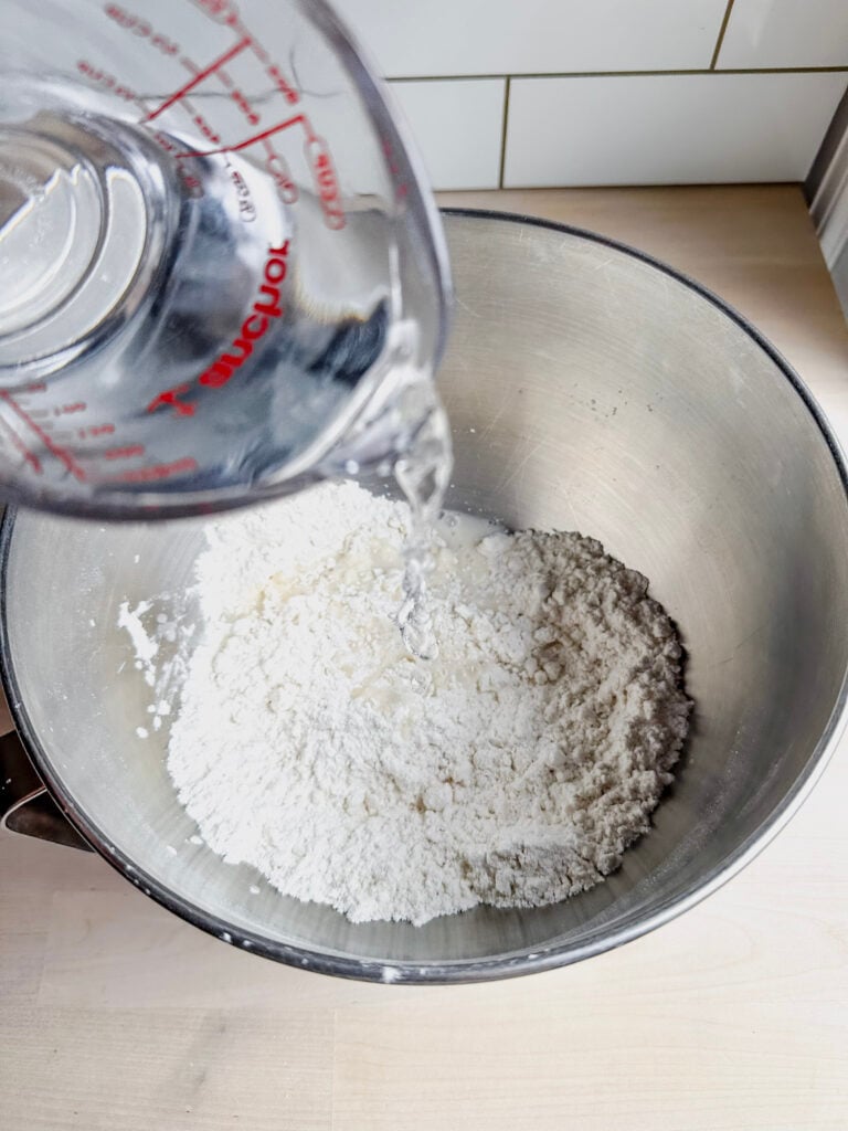 adding water to dry ingredients in mixing bowl