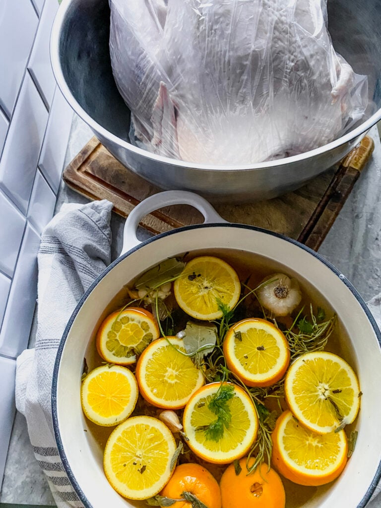 stockpot full of brine solution and a turkey in a large bowl
