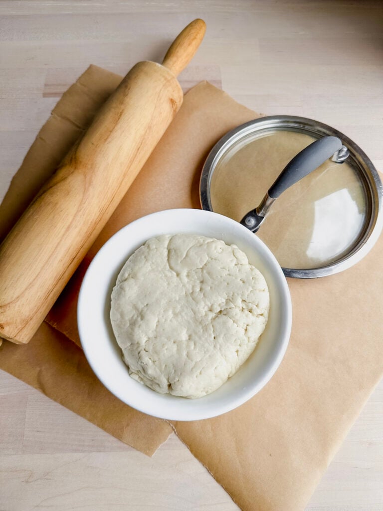 rolling pin, tortilla dough, and saucepan lid on workstation