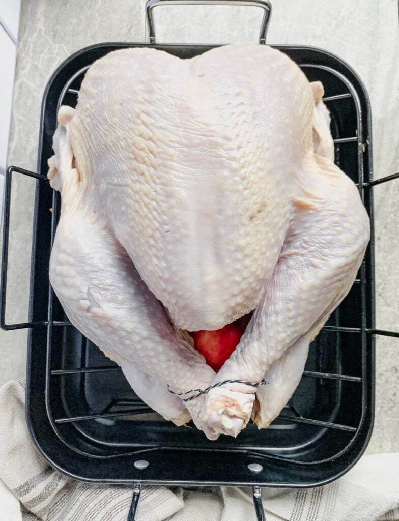 raw turkey in a black roasting pan