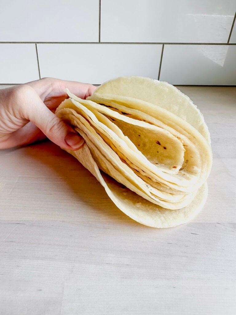 stack of homemade gluten free flour tortillas curled together to show pliability