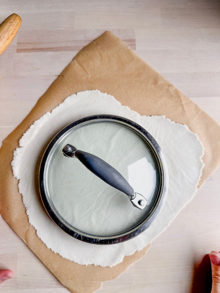 using a saucepan lid to cut the pressed tortilla dough into a circle