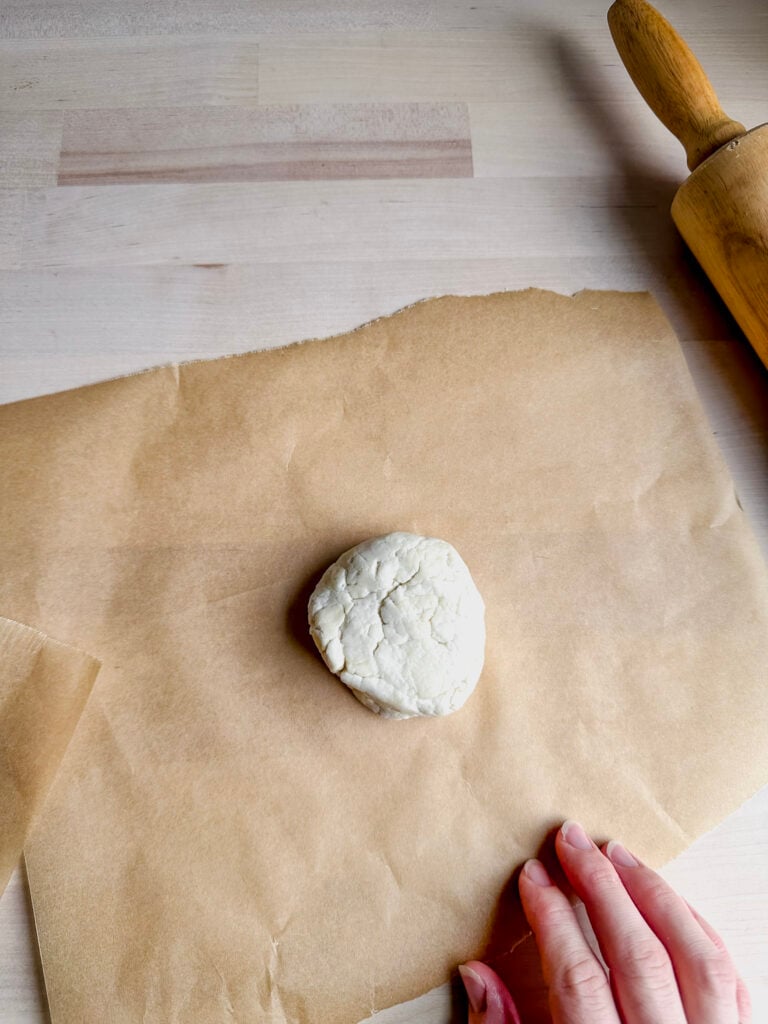 rough ball of gluten free tortilla dough on a piece of parchment paper