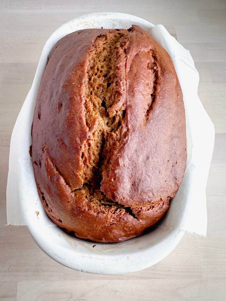 white ceramic bread loaf pan with finished baked loaf of pumpkin bread