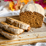 partially sliced loaf of gluten free pumpkin bread on a wooden cutting board