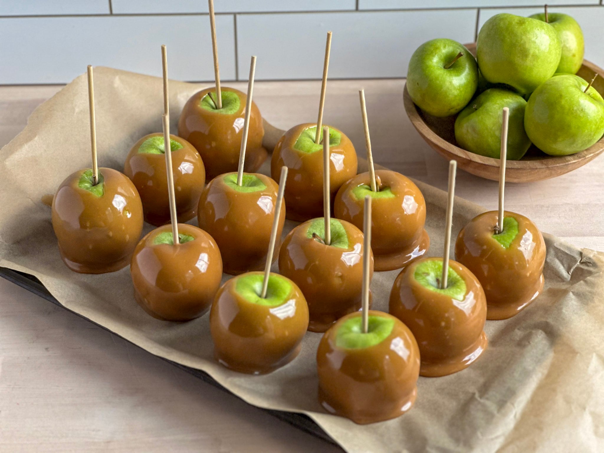 tray of green apples with brown caramel on a stick