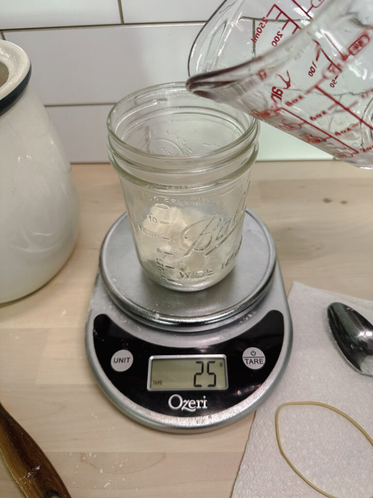 glass mason jar with brown rice flour in it and adding 25 grams purified water to it