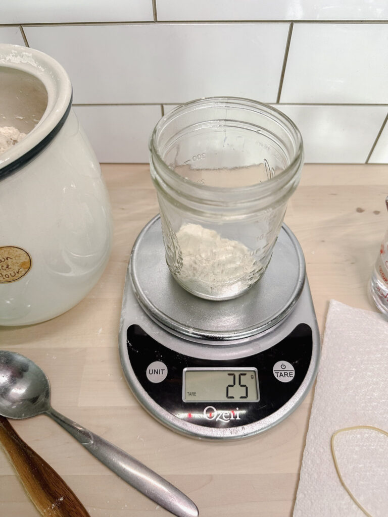 glass mason jar sitting on a kitchen scale. The jar has 25 grams of brown rice flour