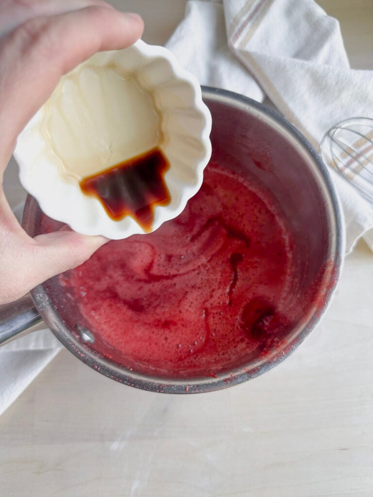 pouring vanilla into the strawberry sauce
