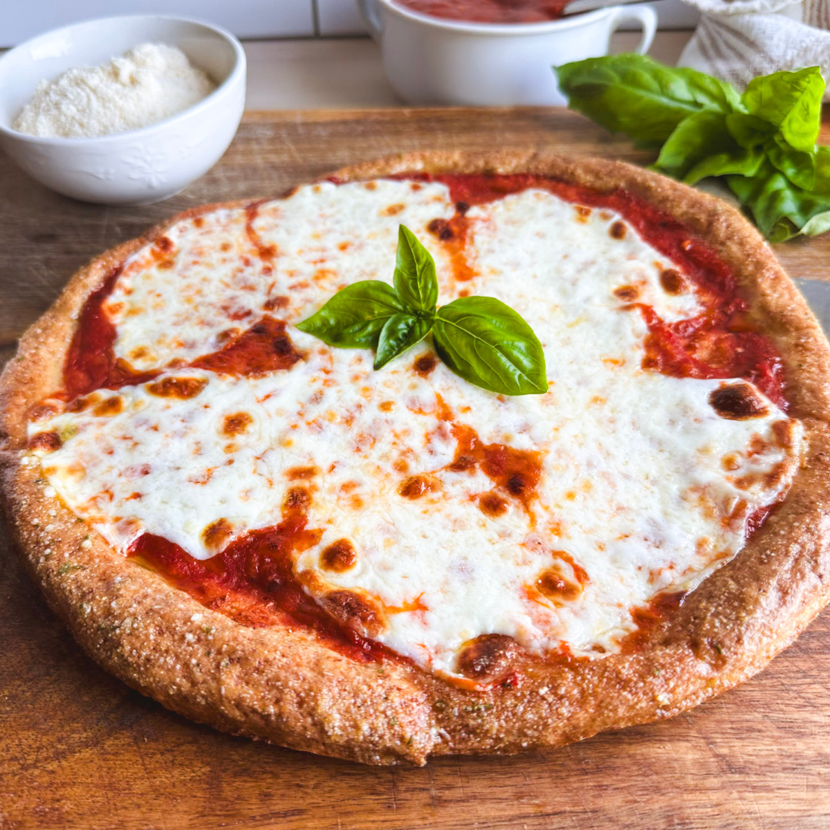whole gluten free pizza sits on cutting board ready to slice